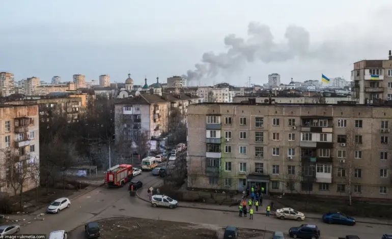 Kyiv skyline during a Russian drone attack with emergency responders and smoke visible in the distance.