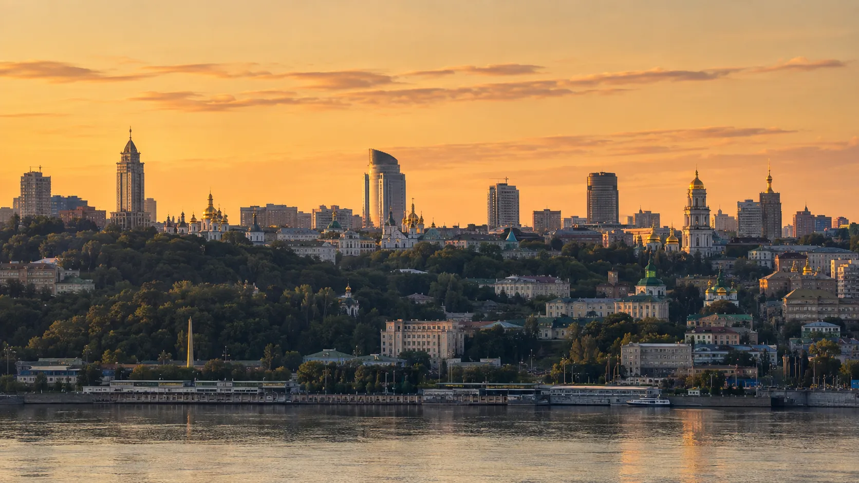 Kyiv skyline showing historic hills, the Dnieper River and modern high-rise buildings.